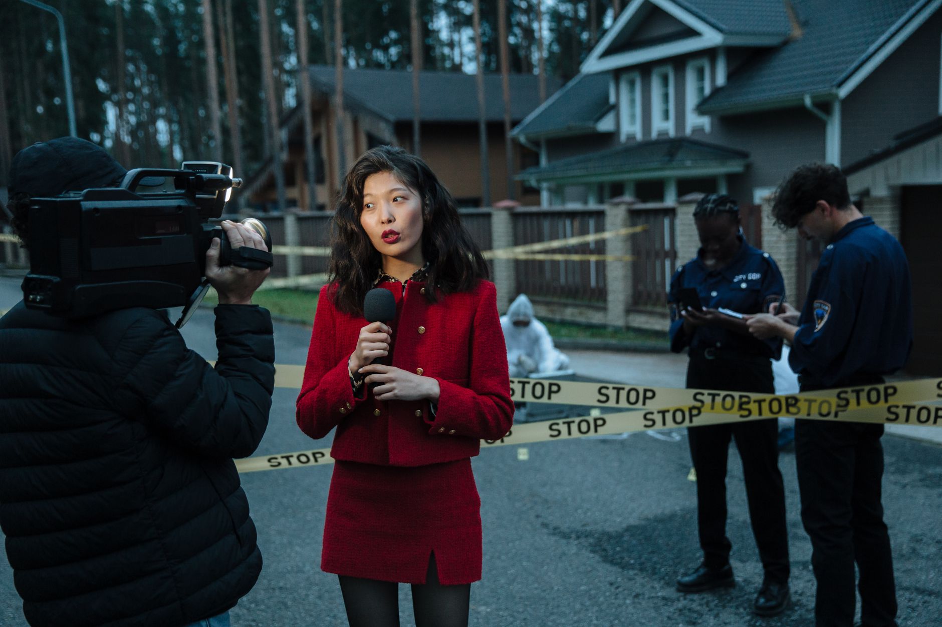 A journalist reporting from a crime scene with police officers and cameraman. — examplearticle