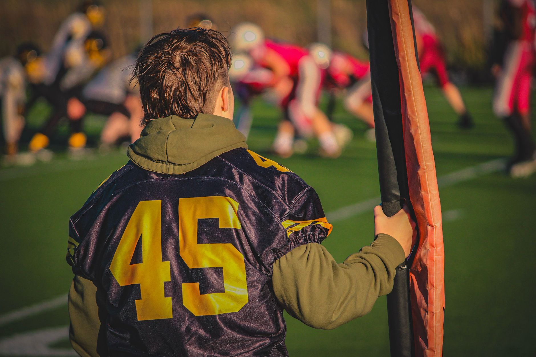 A young football player stands on the sidelines during a team match. — Sportsurge Giving Viewers Control Over Their Sports Wa